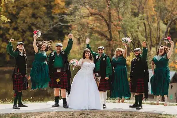 Two adults and four children outside wearing kilts