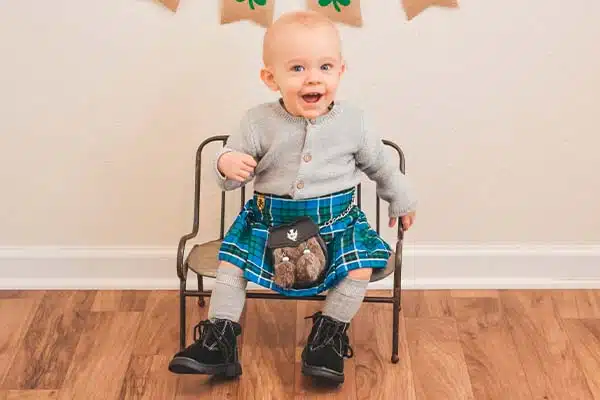 Two children wearing kilts outside
